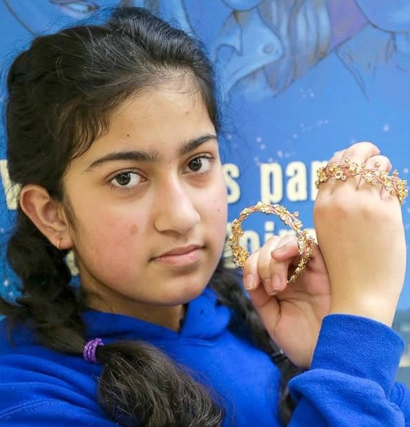 Portrait of a teenage girl holding bracelets close to her face.