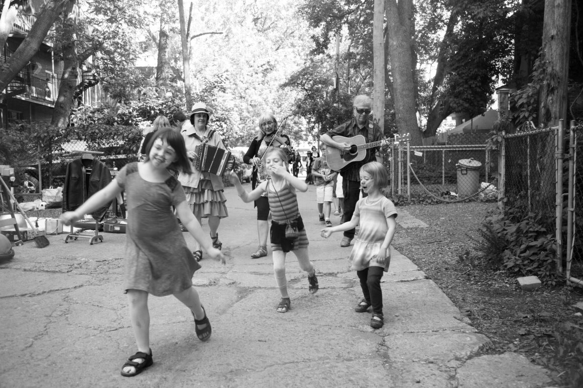 A group of three children are having fun with musicians in the background.
