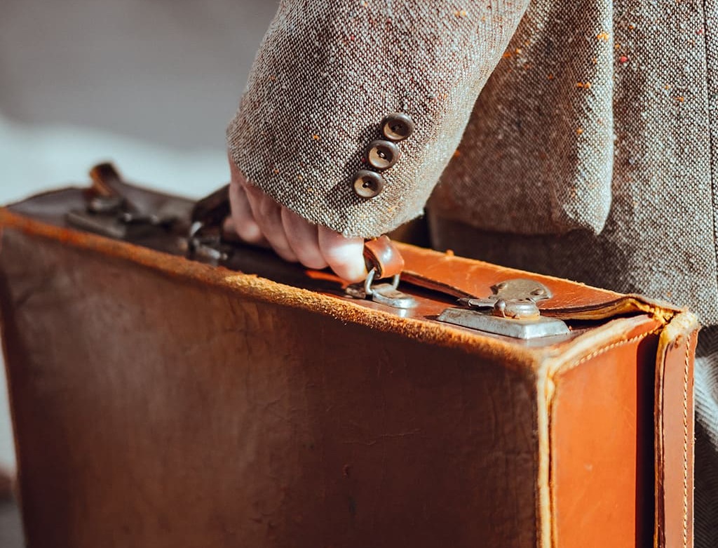 Close-up on a hand carrying a suitcase.