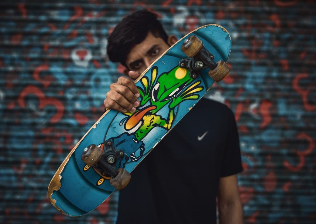 Jeune homme tenant une planche à roulette personnalisée.
