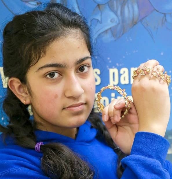 Portrait d’une adolescente tenant des bracelets près de son visage.