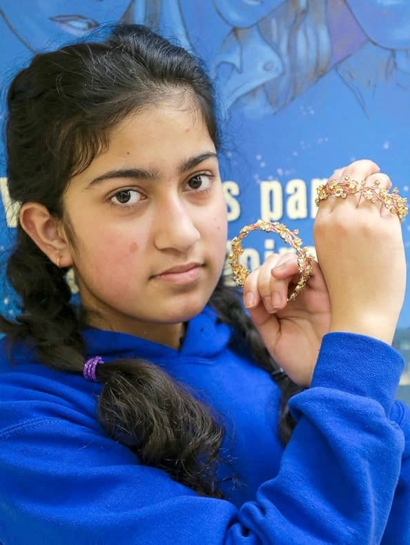 Portrait of a teenage girl holding bracelets close to her face.