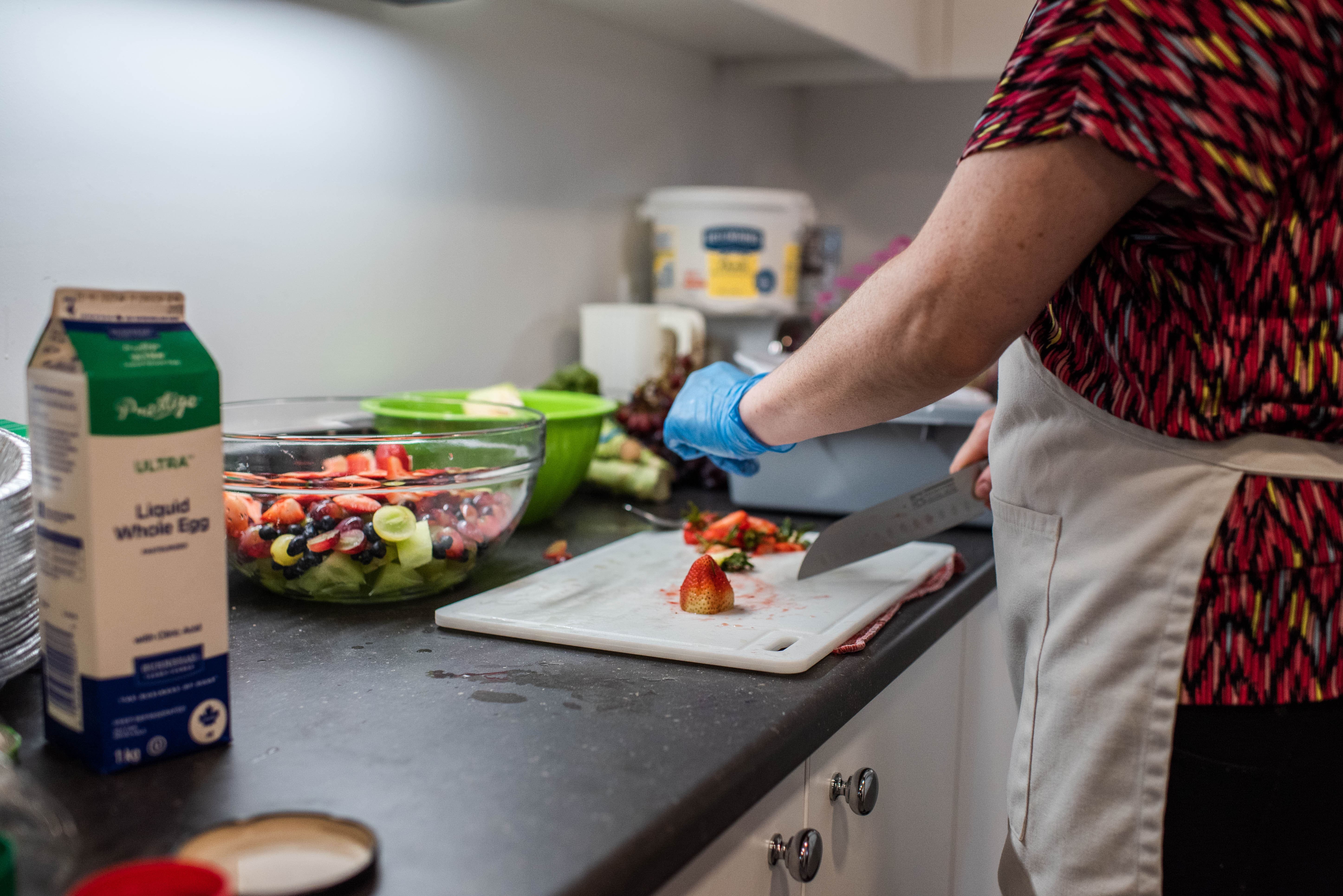 Une personne coupe des fraises pour une salade de fruits