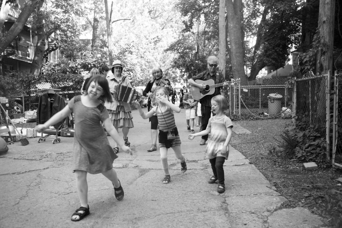 Un groupe de trois enfants s'amusent avec des musiciens en arrière-plan.