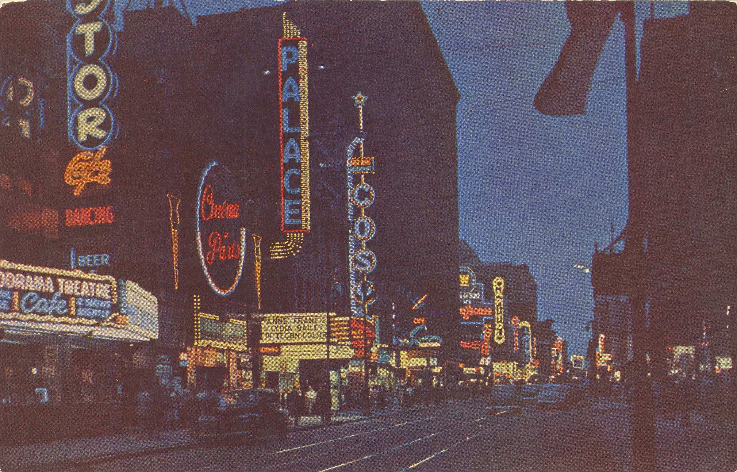 Carte postale présentant la rue Sainte-Catherine en 1952 de nuit avec ses néons lumineux.