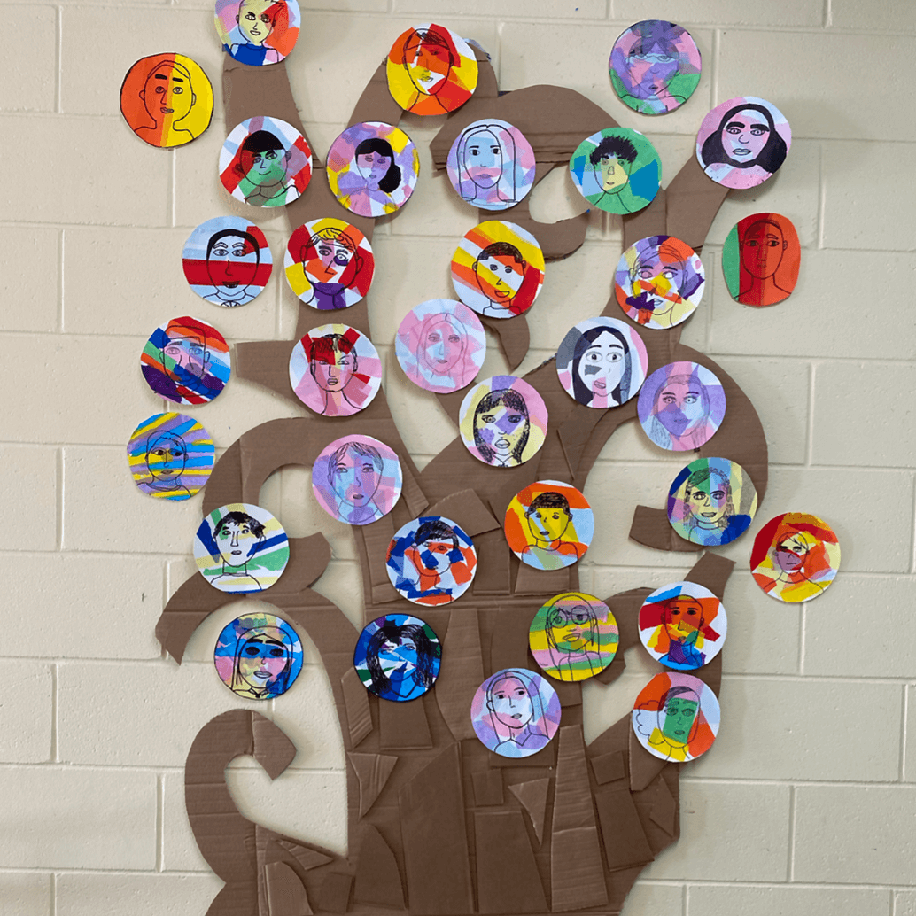 Arbre en carton décoré de dessins d'élèves dans des pastilles colorées formant un feuillage.