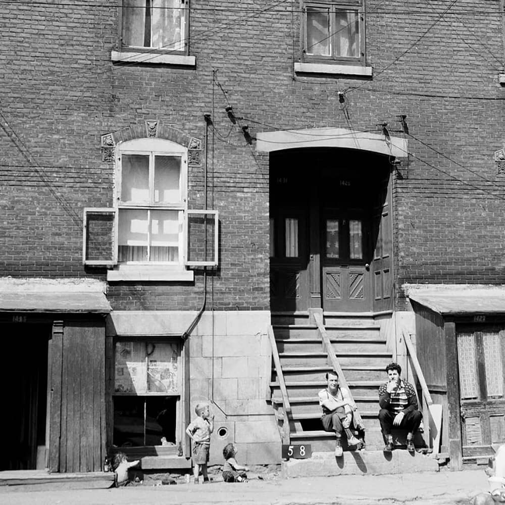 Deux hommes et trois enfants devant un vieille maison